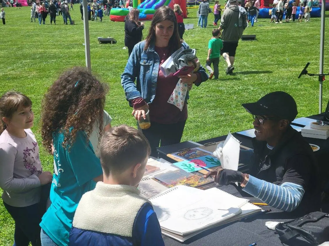 Jean Esther drawing with kids at an outdoor community event
